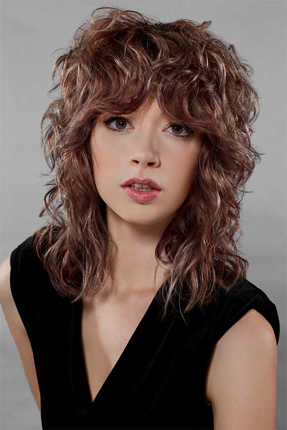 A woman with a texturized wavy mullet and the Style Masters™ products used to create the look