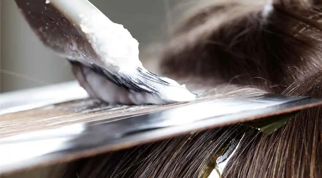 A brush with hair color dye being applied to the hair