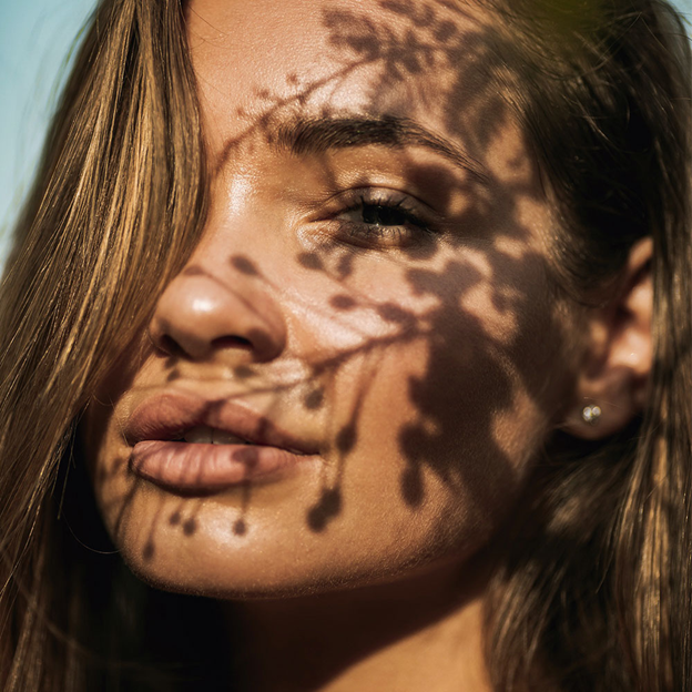 A woman with a shadow of a plant over her face 