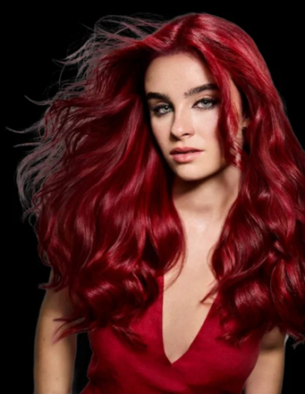Model wearing a red top, with long wavy hair blowing in the wind